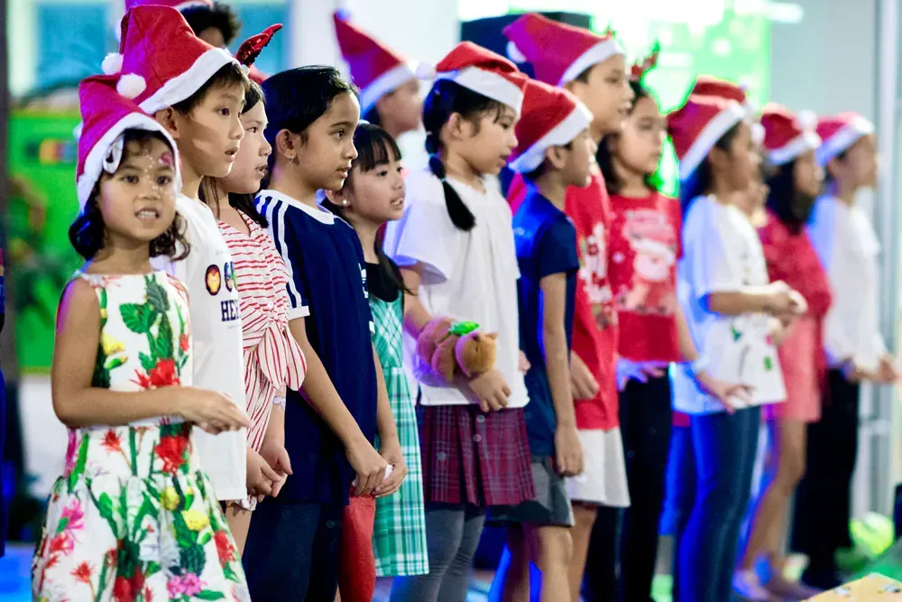 A group of children wearing santa hats are standing in a line.