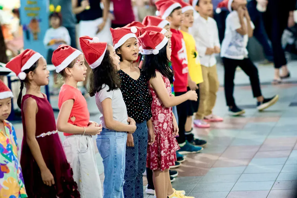 A group of children wearing santa hats are standing in a line.