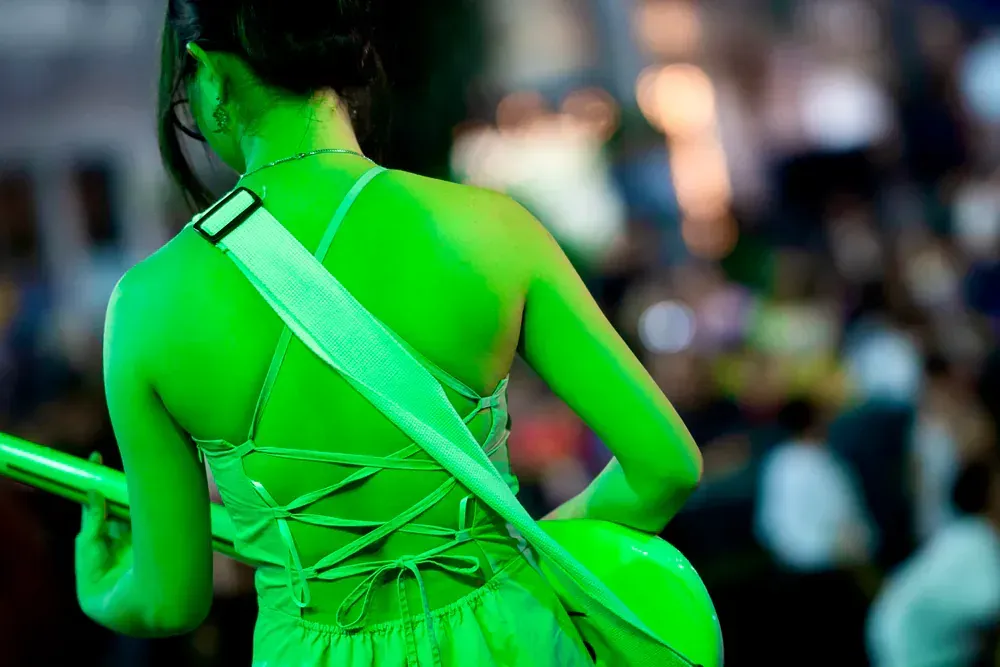 A woman in a green dress is playing a guitar in front of a crowd.