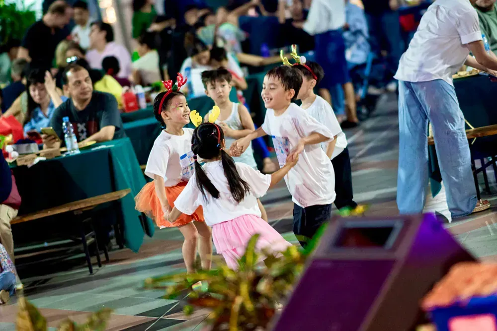 A group of children are dancing in a crowded room.