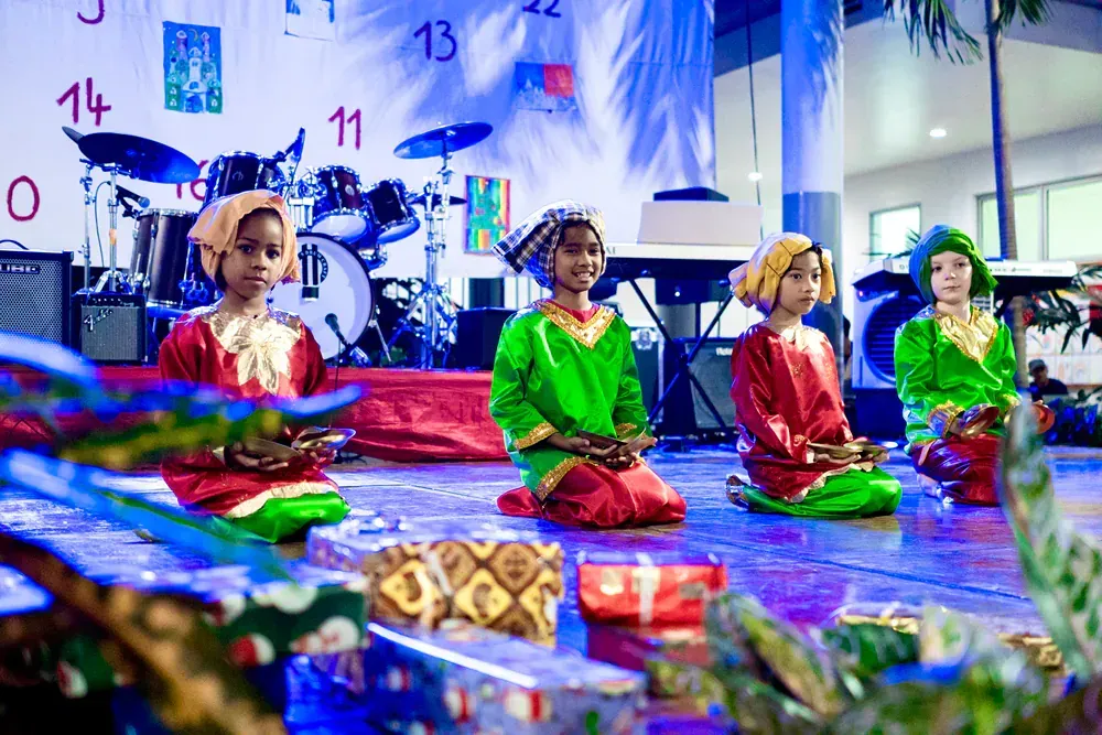 A group of children are kneeling on the floor in front of a drum set.