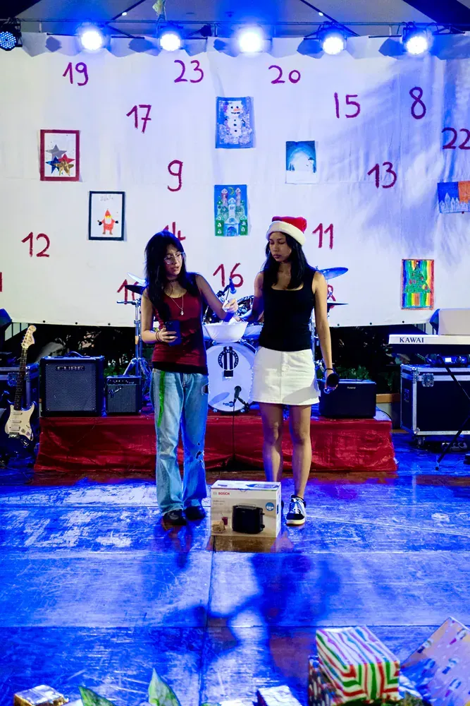 Two women stand on a stage in front of an advent calendar