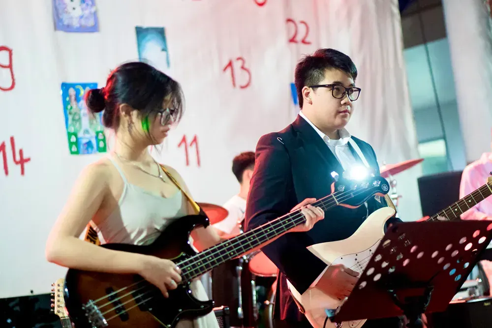A man and a woman are playing guitars in a band.