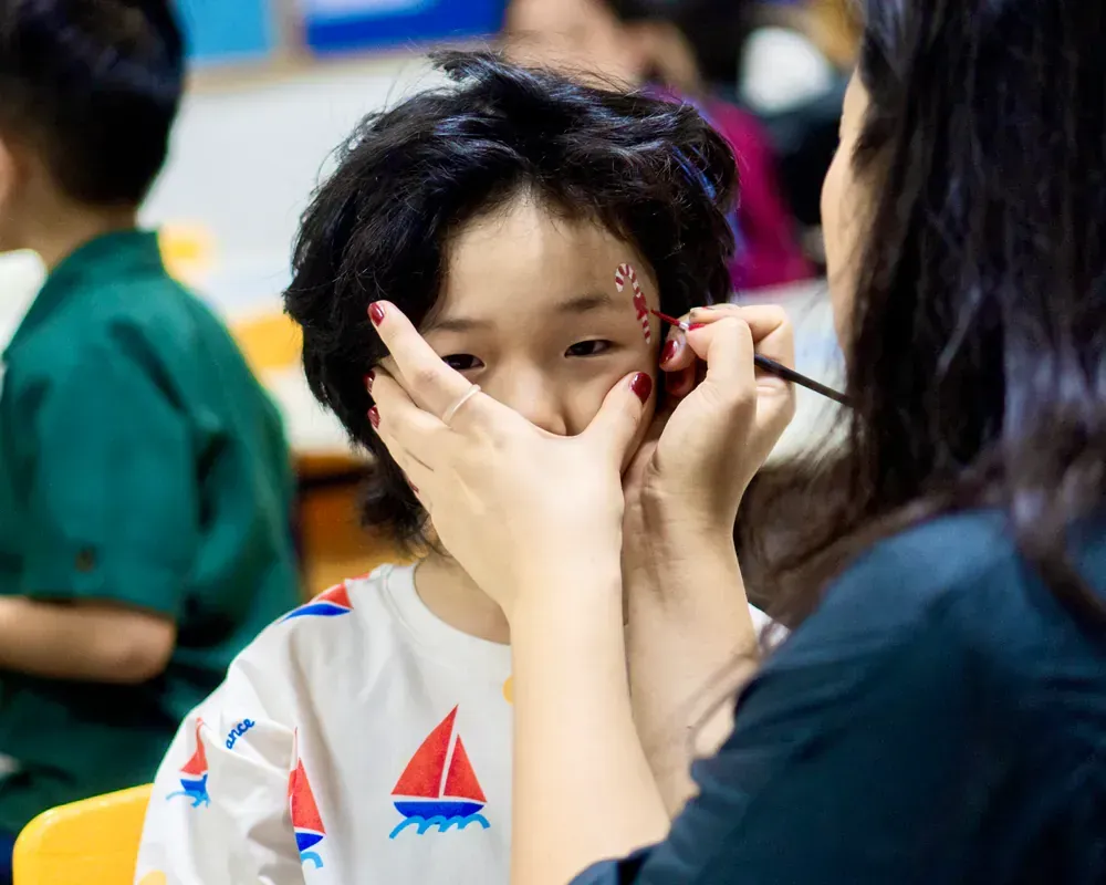 A woman is painting a child 's face with a brush.