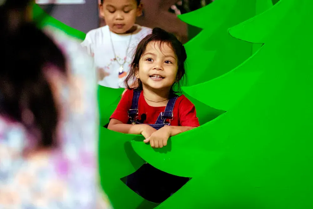 A little girl is sitting on a green slide.