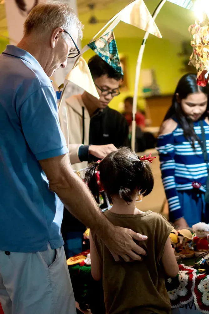A man is putting a christmas hat on a little girl 's head.