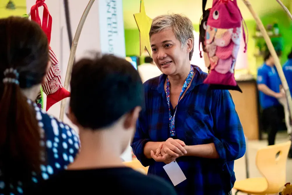 A woman in a blue shirt is talking to a child.