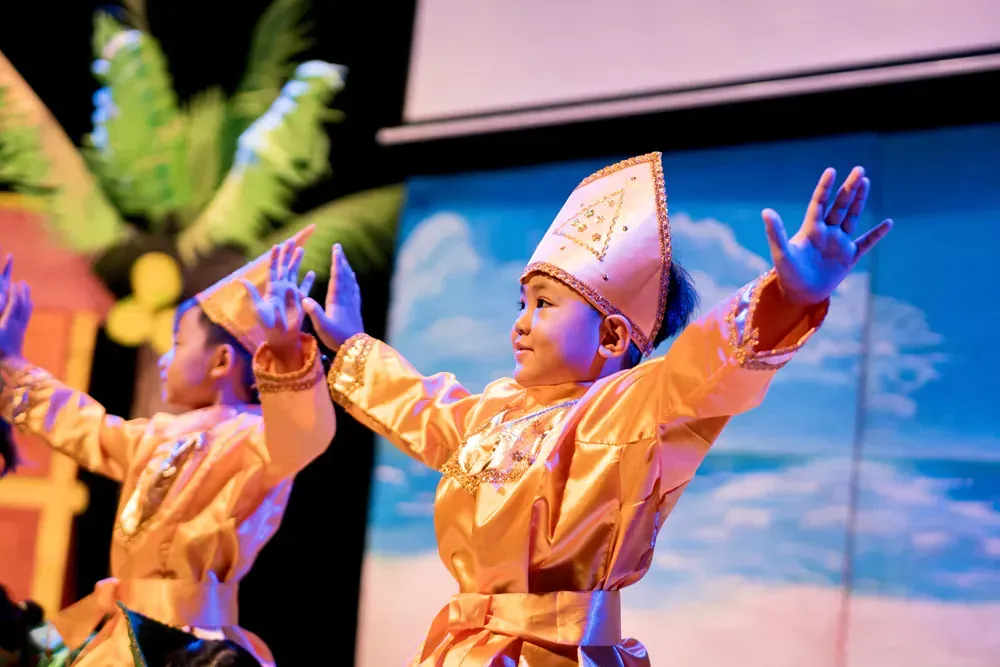 A group of young children are dancing on a stage.