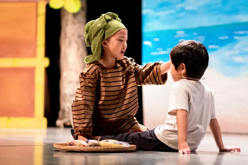 A boy and a girl are sitting on the floor talking to each other.
