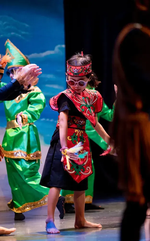 A group of children in traditional costumes are dancing on a stage.