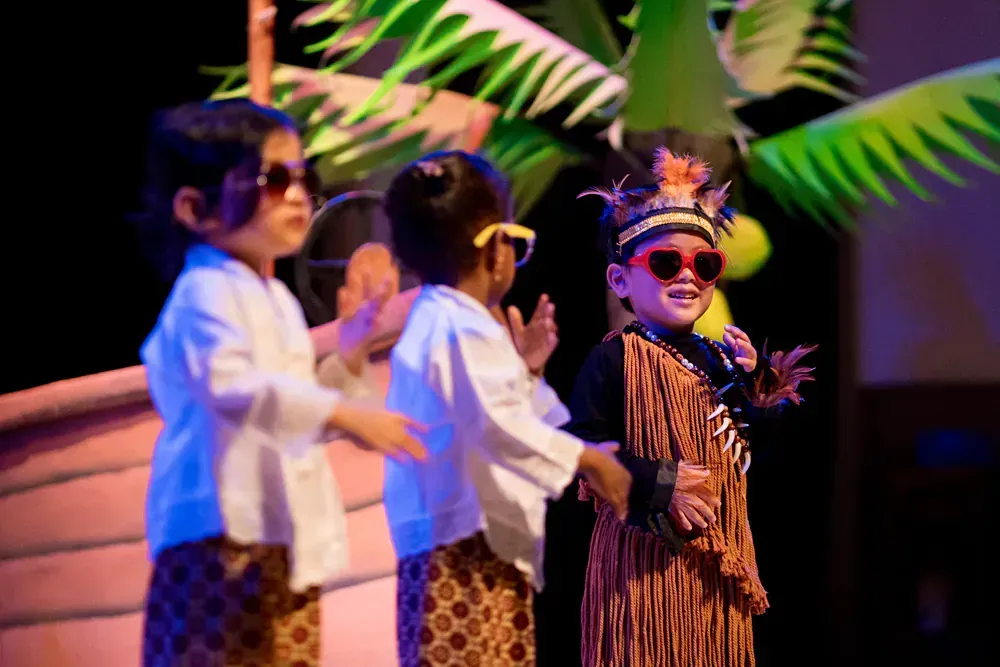 A group of children dressed in native american costumes are standing on a stage.