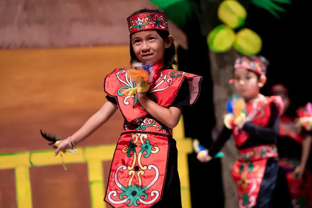 A girl in a red and black costume is dancing on a stage.