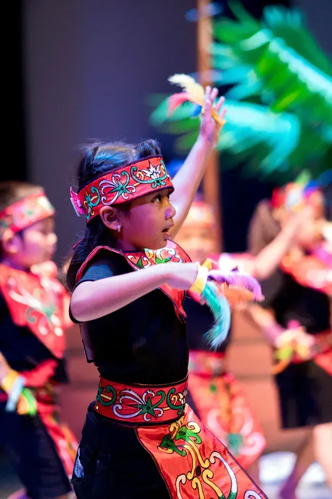A group of young girls are performing a traditional dance on a stage.