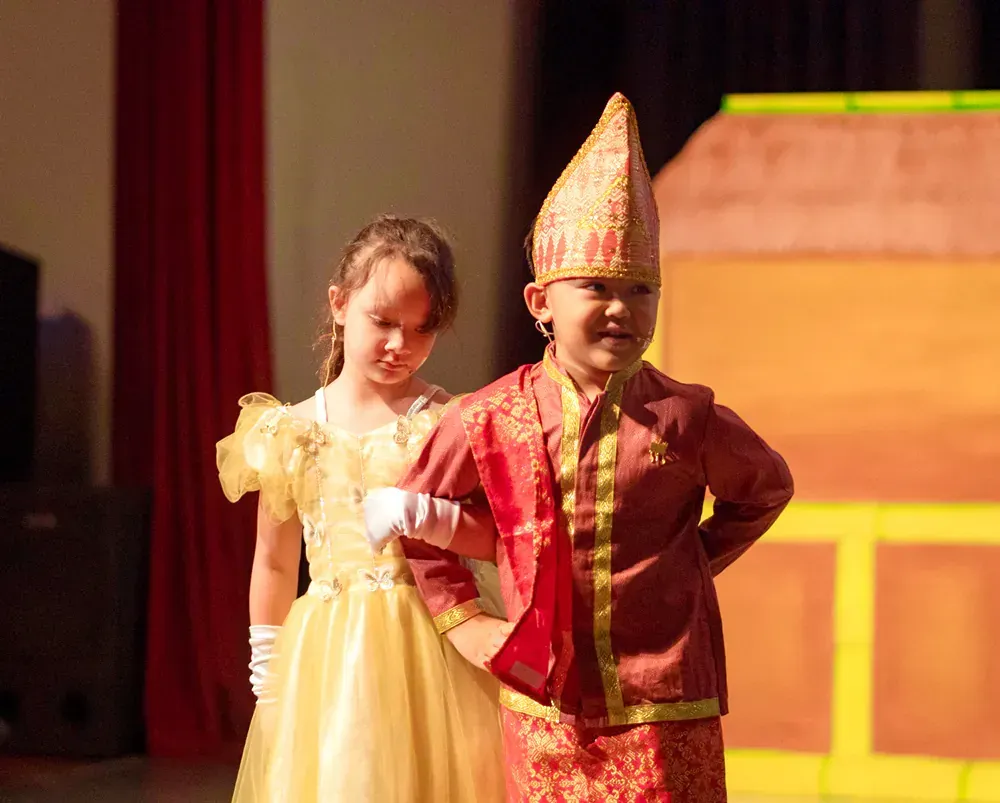 A boy and a girl are dressed in costumes on a stage.