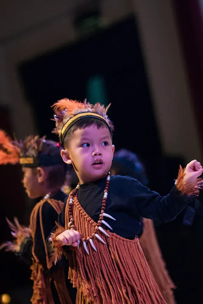 A young boy in a native american costume is dancing on a stage.