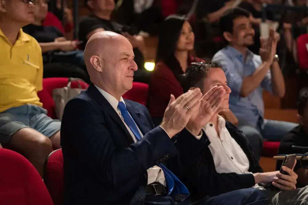 A group of people are sitting in a theater applauding.