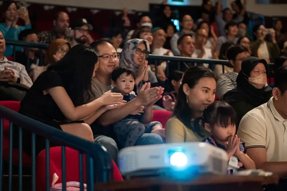 A group of people are sitting in front of a projector in a theater.