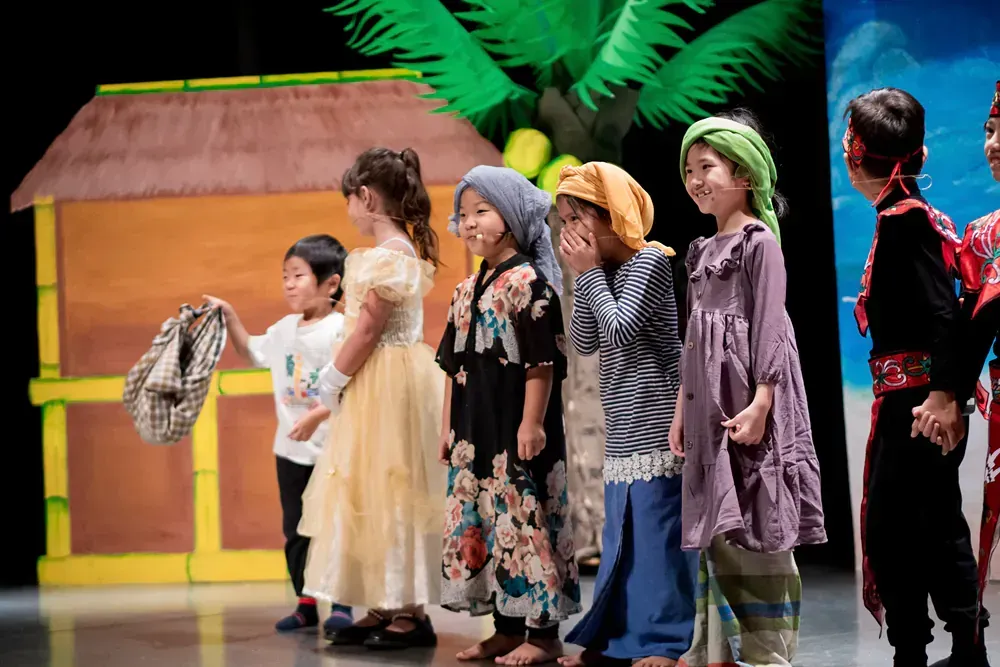 A group of children are standing next to each other on a stage.