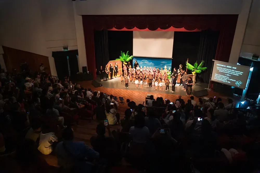 A large group of people are standing on a stage in a theater.