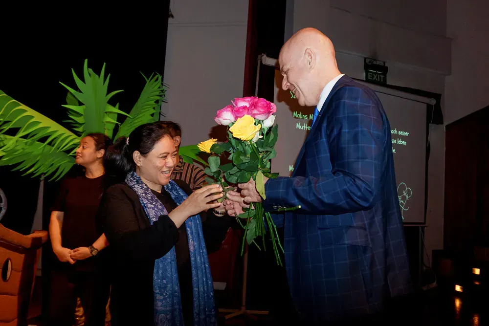 A man in a suit is giving a woman a bouquet of flowers.