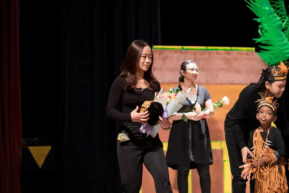 A woman is holding a bouquet of flowers on a stage.