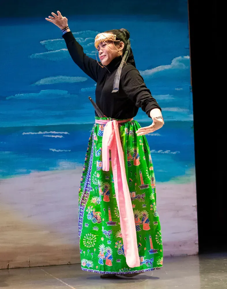 A woman in a green skirt is dancing on a stage.