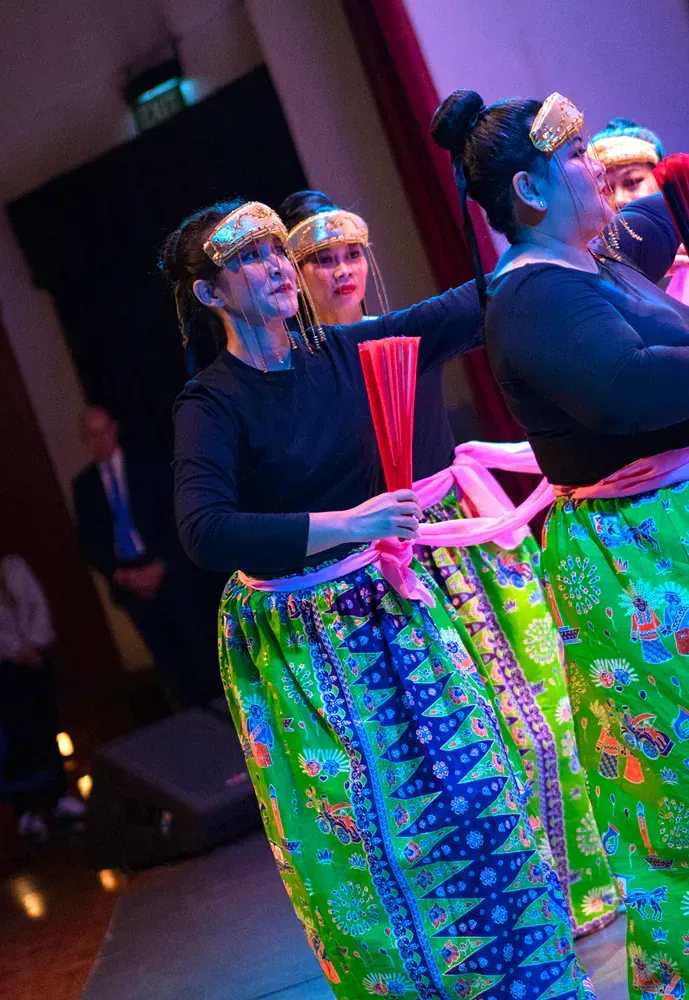 A group of women in colorful skirts are dancing on a stage.