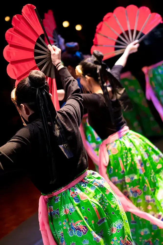 A group of women are dancing with fans in their hands.