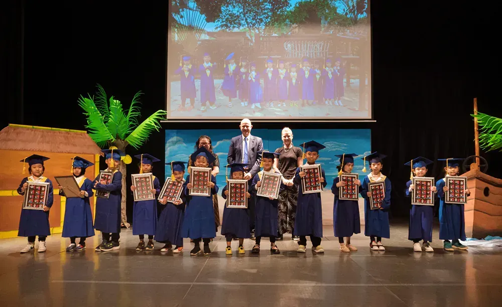 A group of children in graduation caps and gowns are standing on a stage.