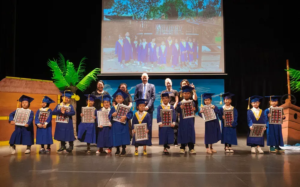A group of children in graduation caps and gowns are standing on a stage.