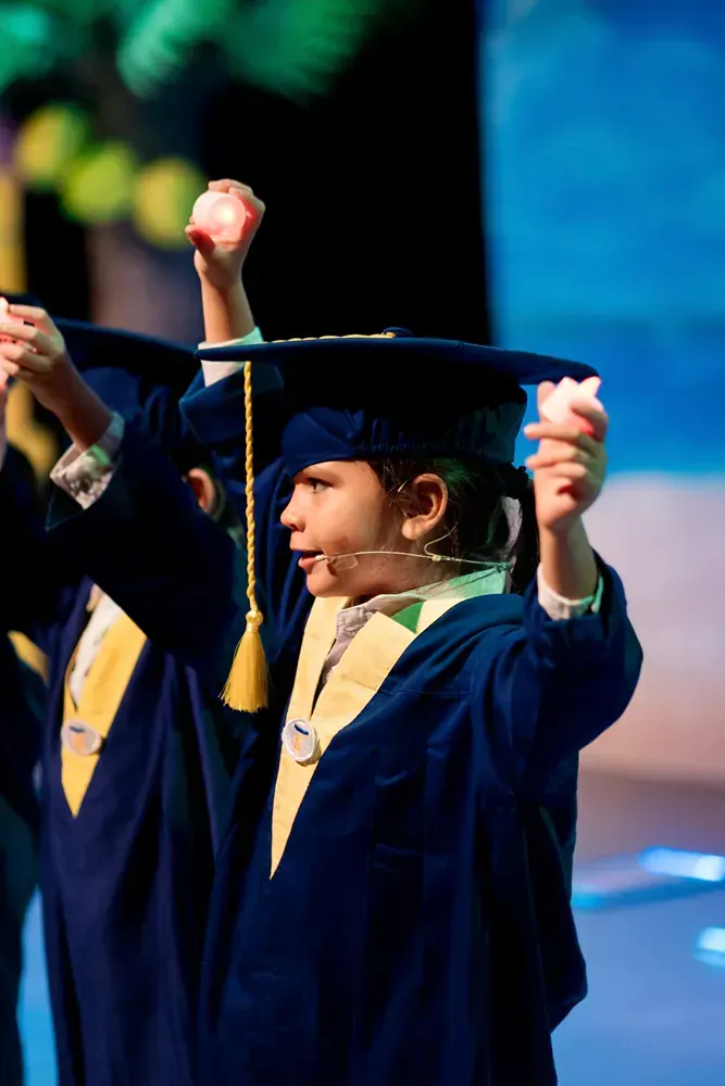 A group of children in graduation caps and gowns are holding candles in their hands.