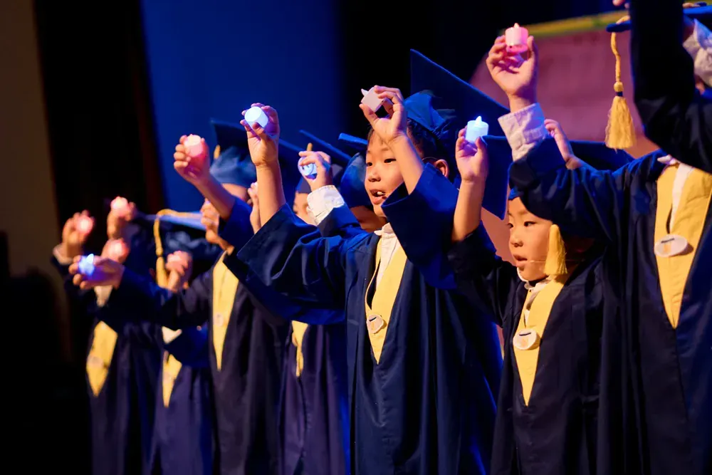 A group of young graduates are holding candles in their hands.