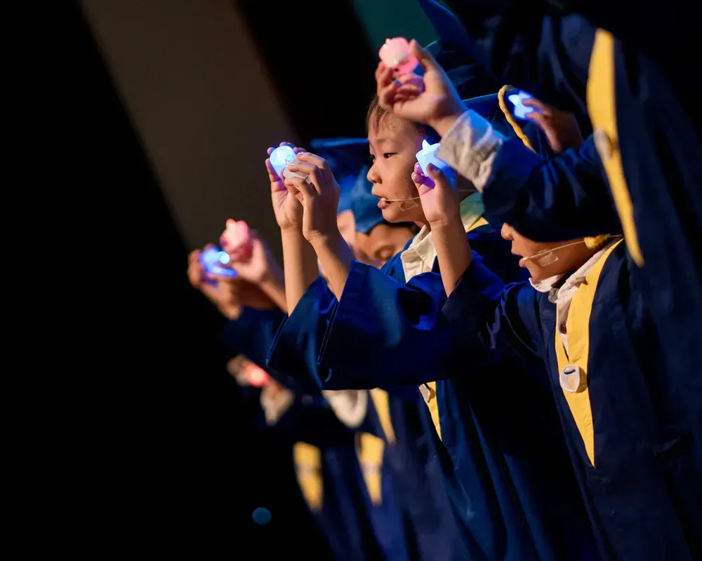 A group of children in graduation gowns are holding candles in their hands