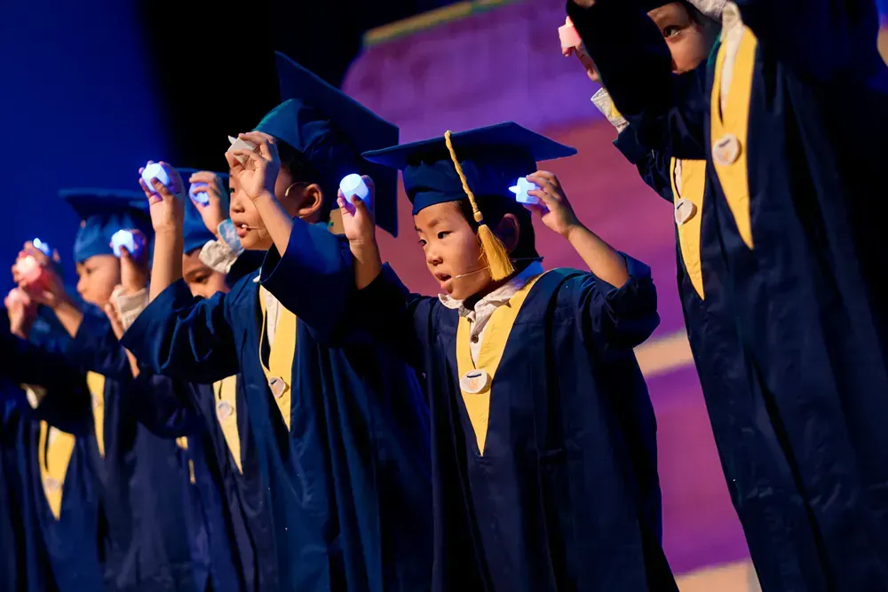 A group of young graduates are holding their hands up in the air