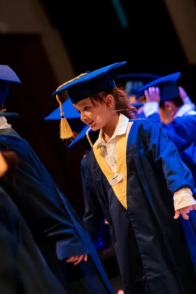 A girl in a graduation cap and gown is standing in a line with other graduates.