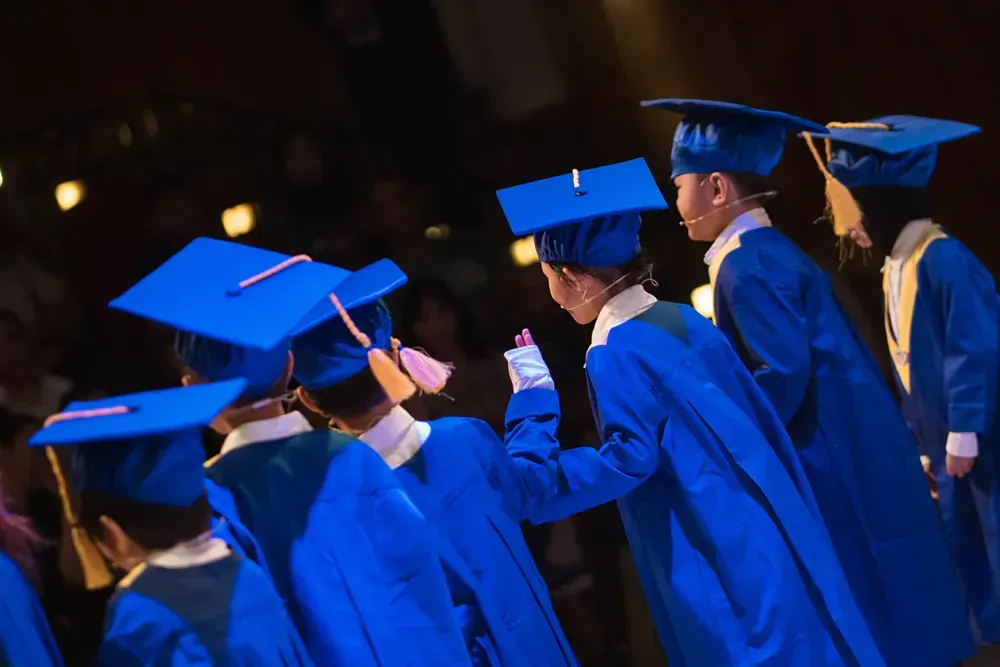 A group of graduates in blue gowns and caps are standing on a stage.
