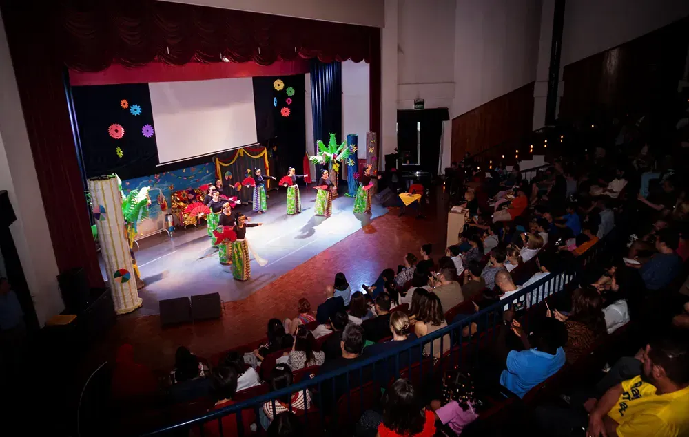 A group of people are sitting in an auditorium watching a performance on stage.
