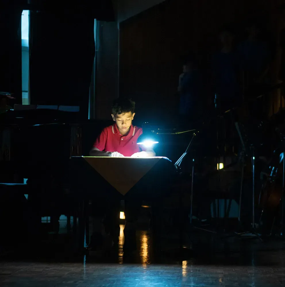 A young boy is reading a book in the dark