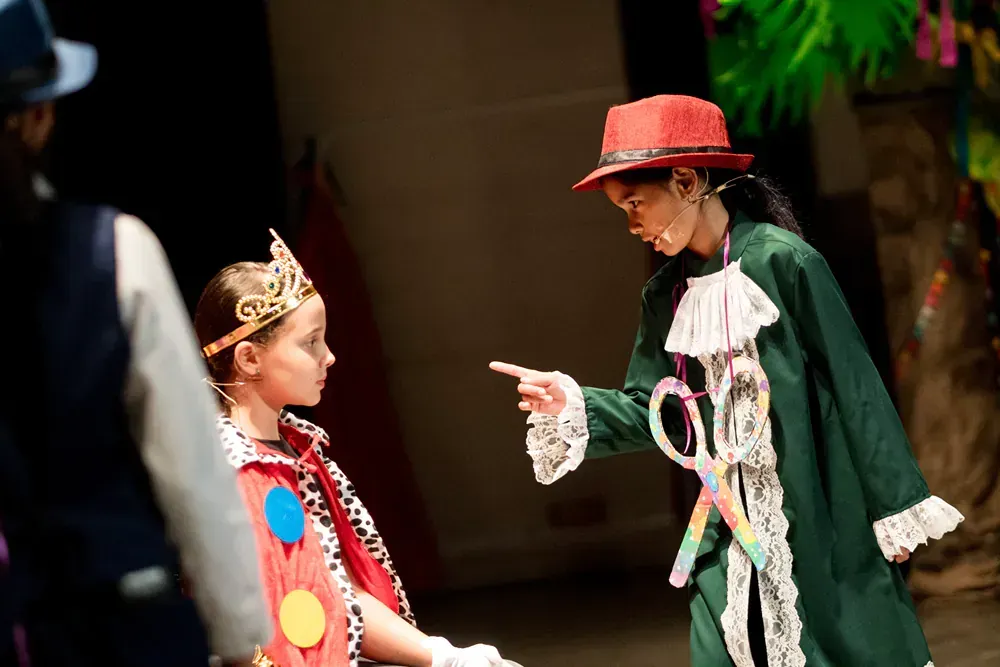 A woman in a red hat is pointing at another woman in a green coat.