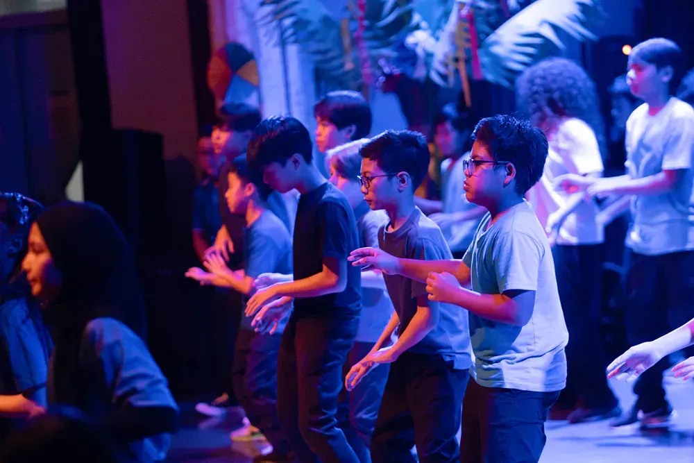 A group of young people are dancing on a stage in a dark room.
