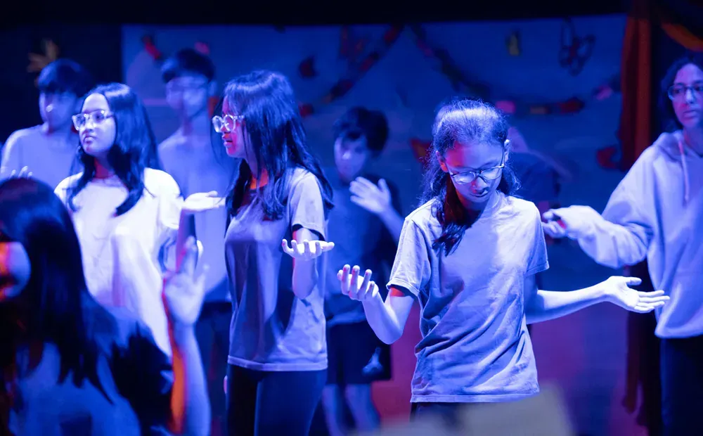 A group of people are dancing on a stage in a dark room.