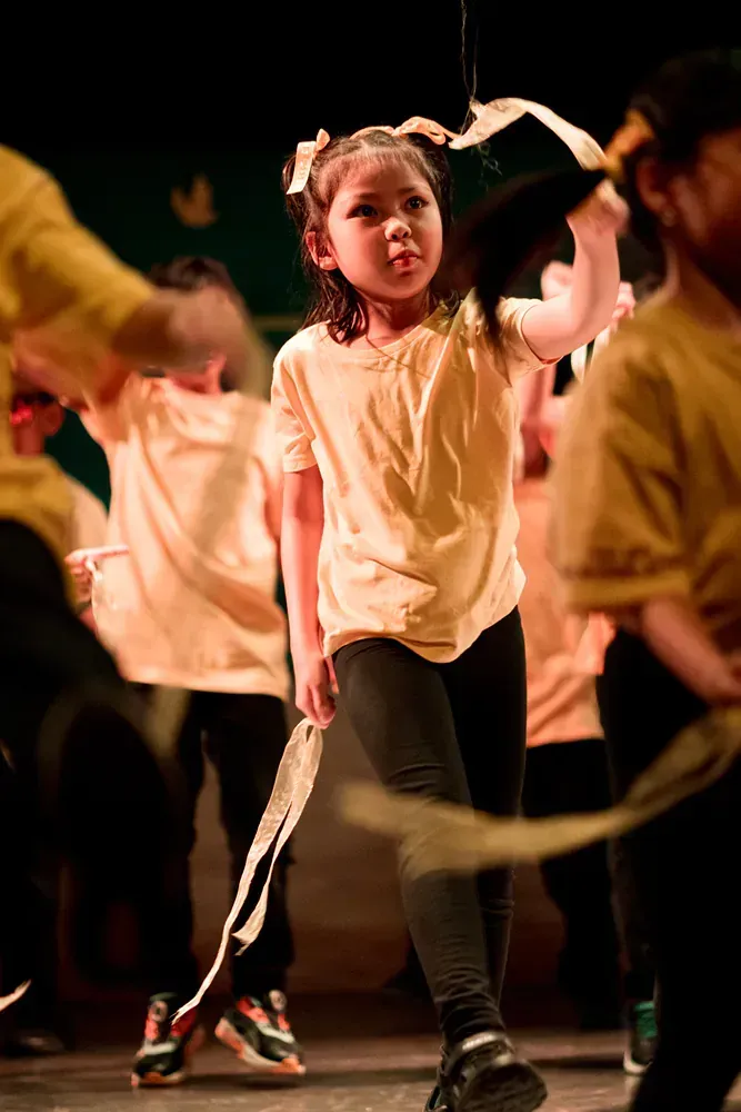 A group of young children are dancing on a stage.
