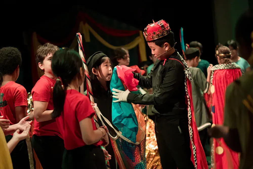 A group of children dressed in costumes are standing on a stage.