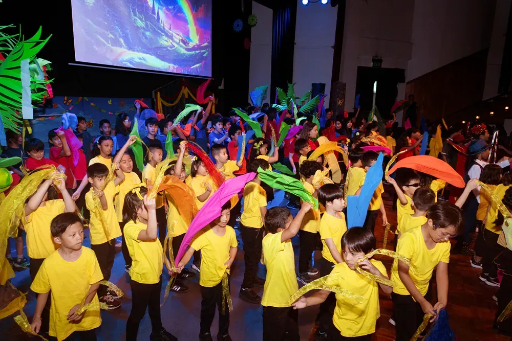 A group of children are dancing in front of a large screen.