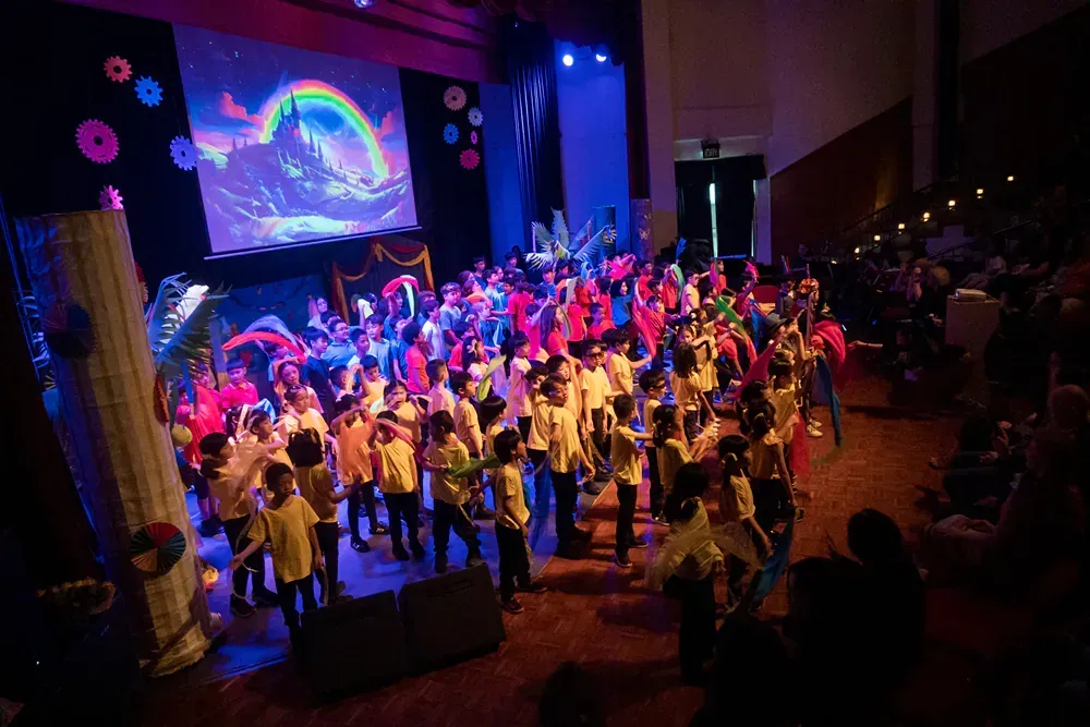 A large group of children are dancing on a stage.