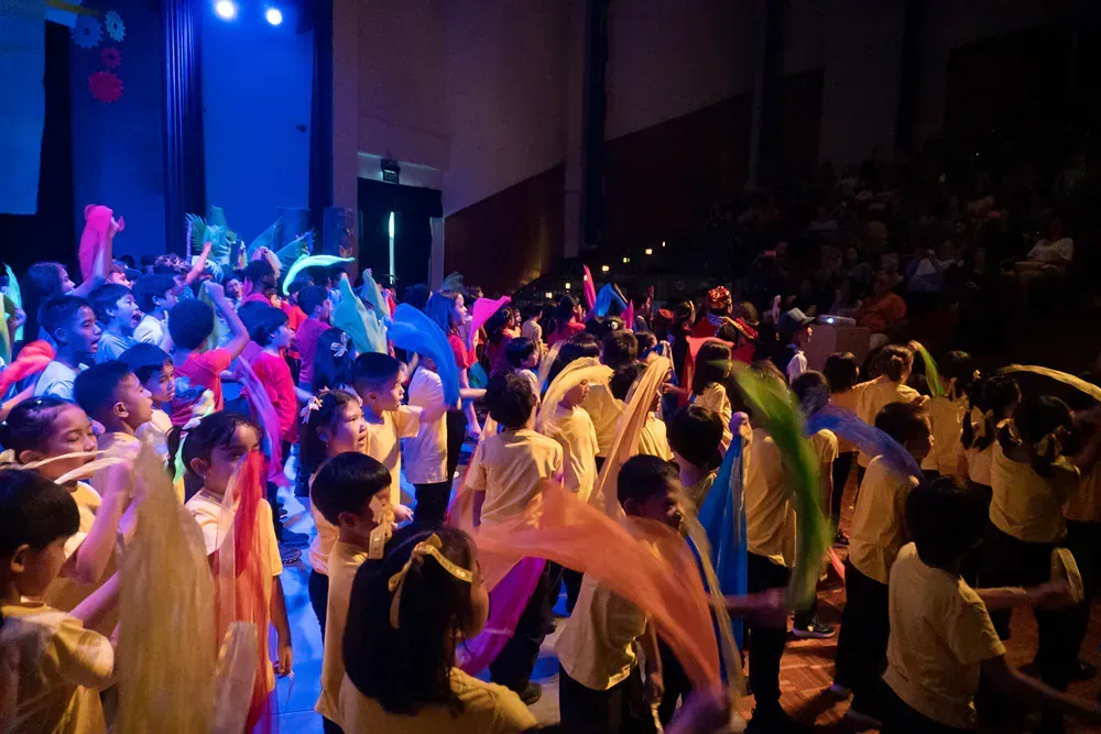 A large group of children are dancing on a stage.