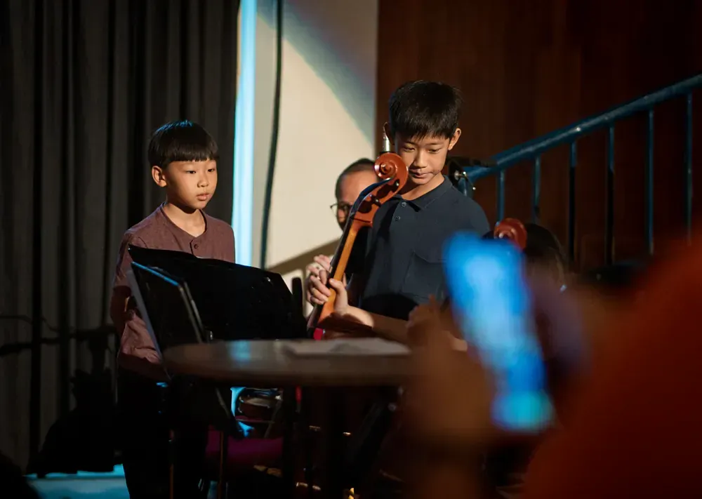 A group of young children are playing instruments on a stage.