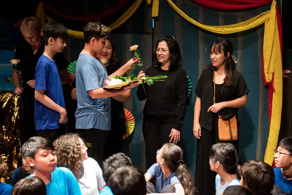 A group of children are sitting in front of a stage.