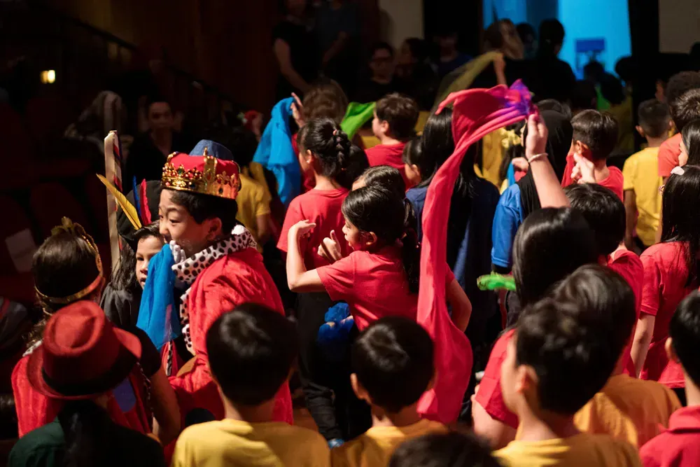 A large group of children are dancing in a room.