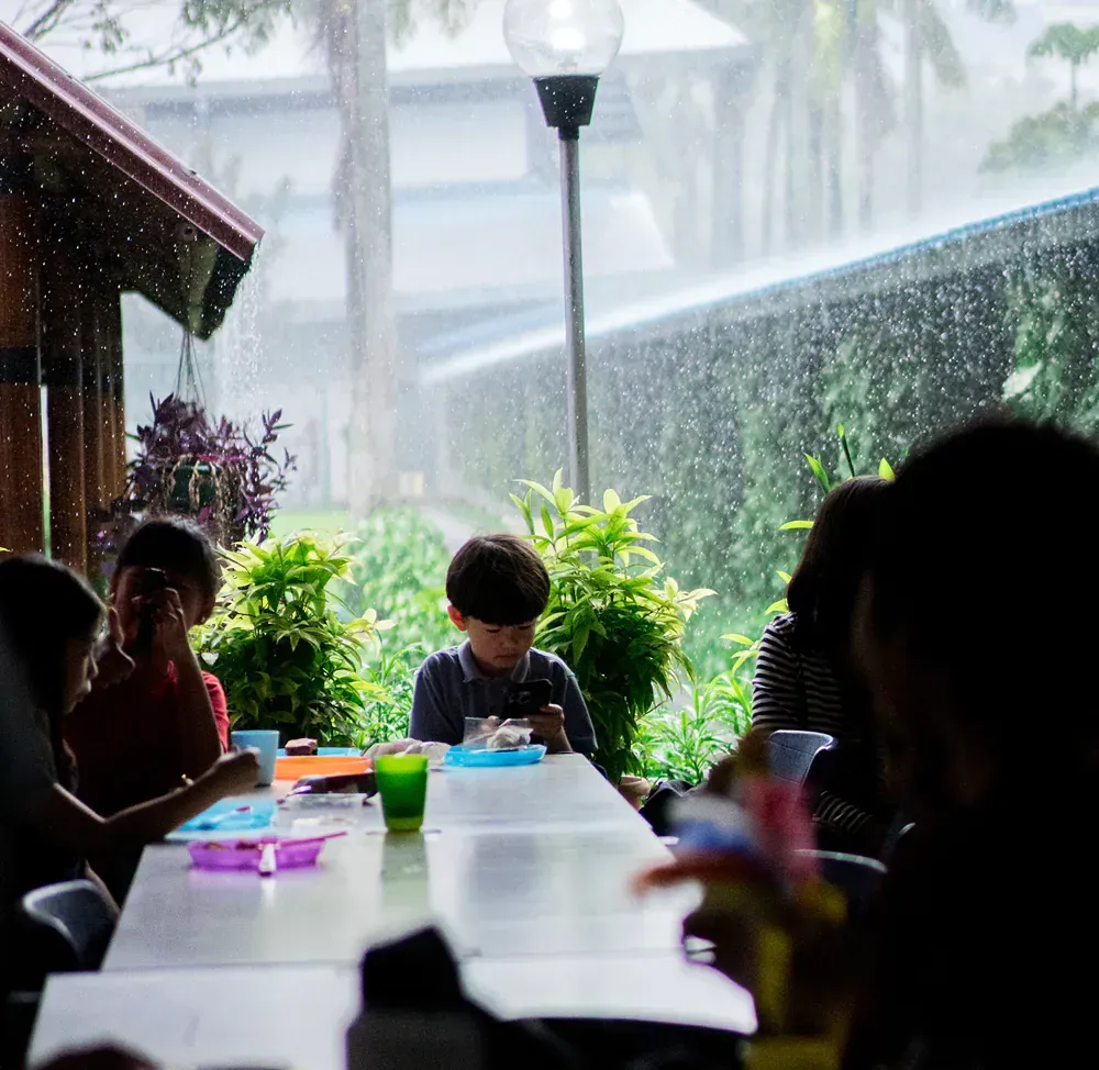A group of people are sitting at a table in the rain.
